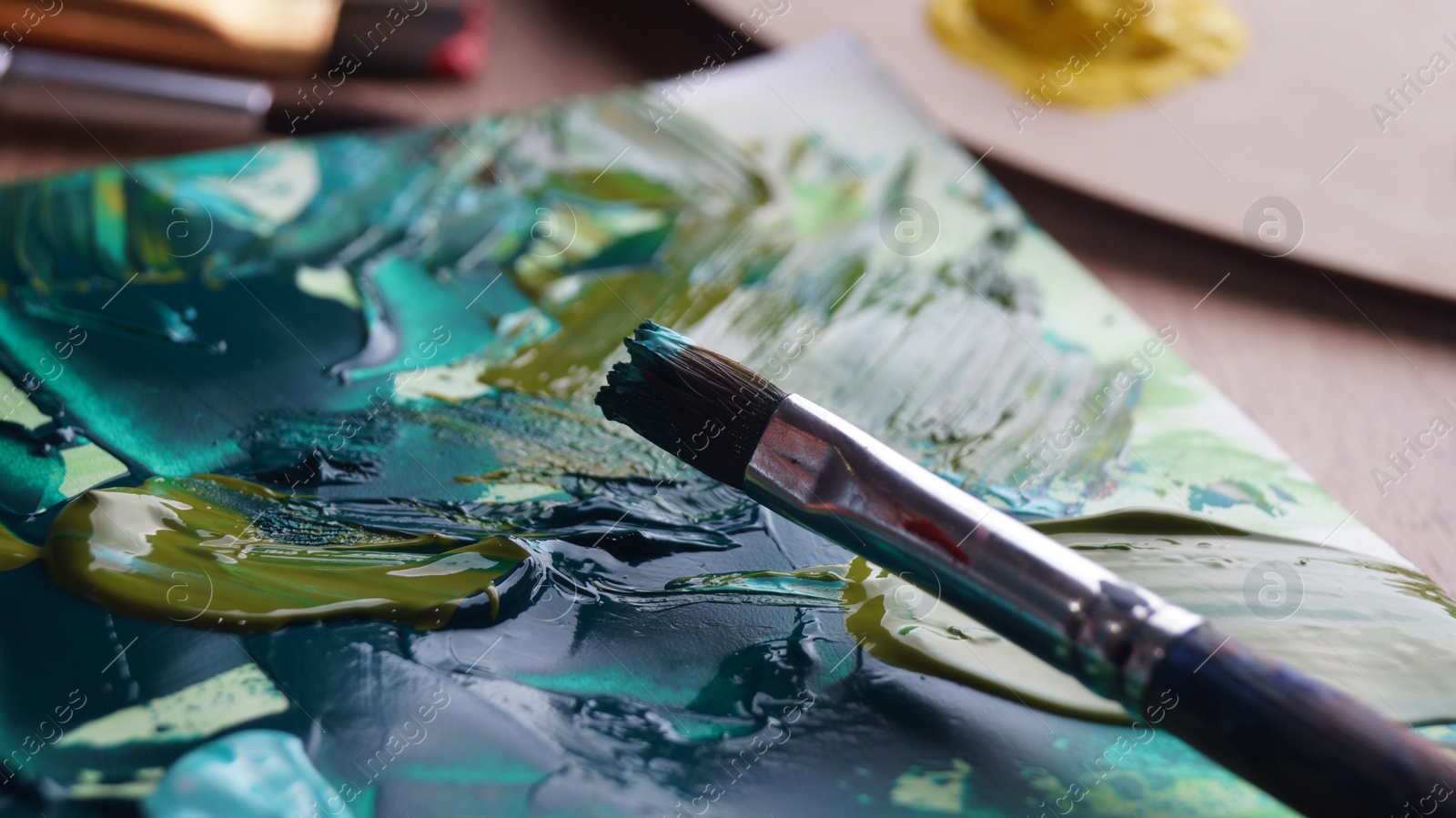 Photo of Brush on artist's canvas with mixed paints, closeup