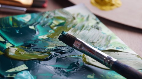 Brush on artist's canvas with mixed paints, closeup