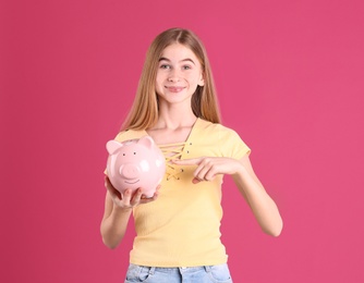 Photo of Teen girl with piggy bank on color background