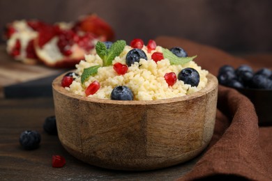 Bowl of tasty couscous with blueberries, pomegranate and mint on table, closeup