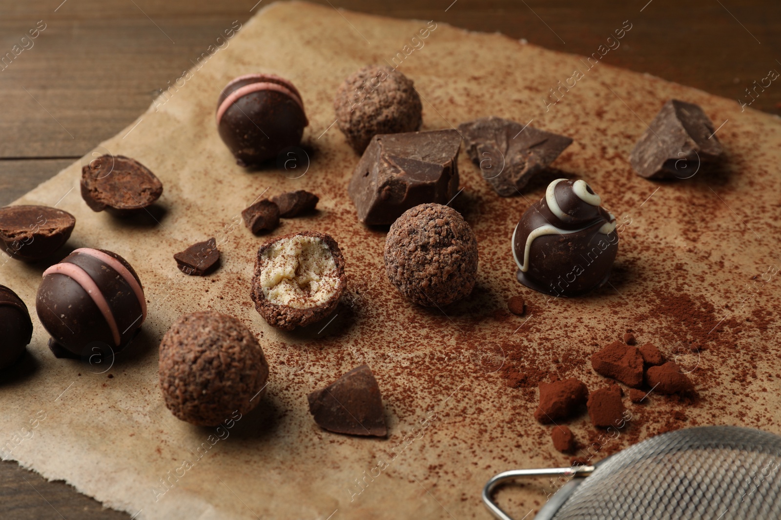 Photo of Different delicious chocolate truffles on wooden table, closeup