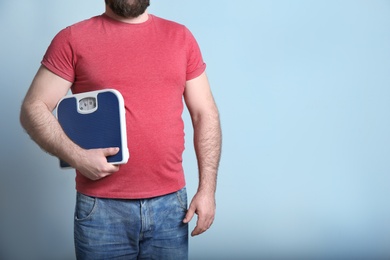 Overweight man with scale on color background