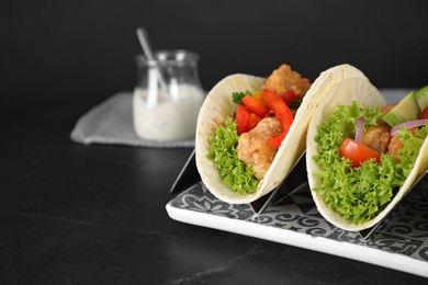 Photo of Delicious fish tacos served on black table, space for text