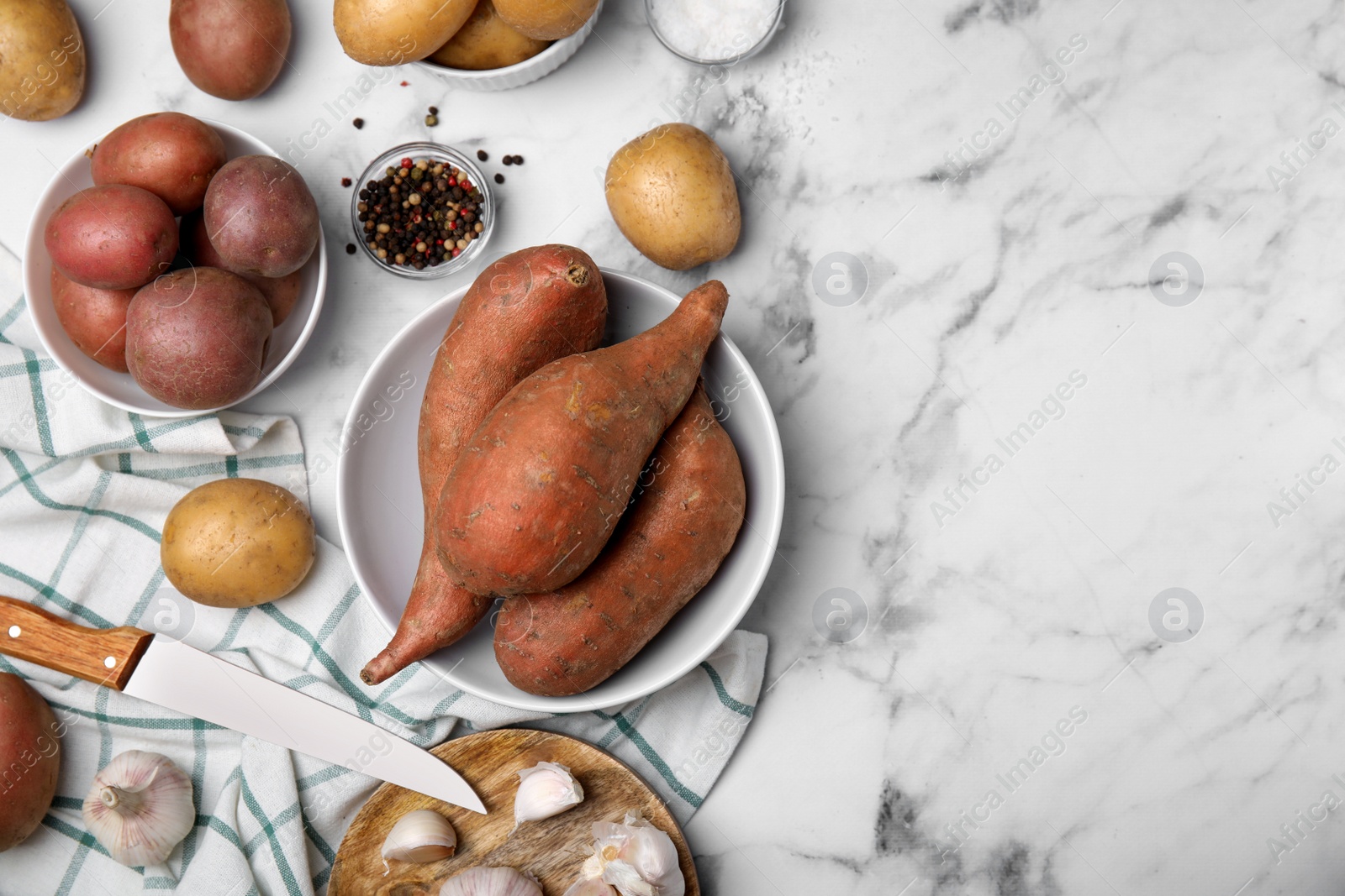 Photo of Different types of fresh potatoes on white marble table, flat lay. Space for text