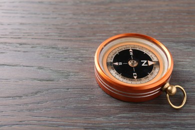 One compass on wooden table, space for text