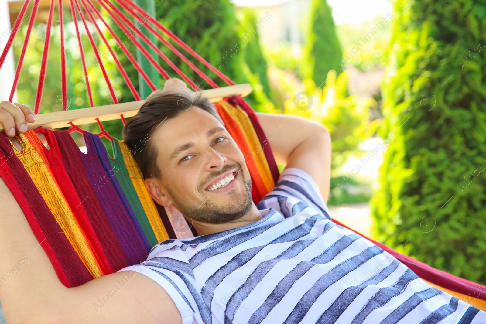 Photo of Man relaxing in hammock outdoors on warm summer day