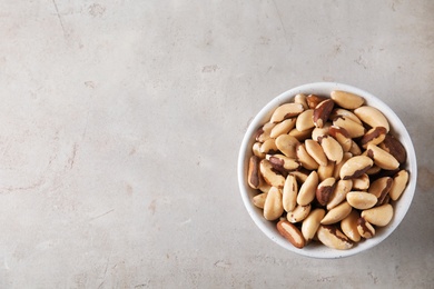 Photo of Bowl with tasty Brazil nuts and space for text on grey background, top view