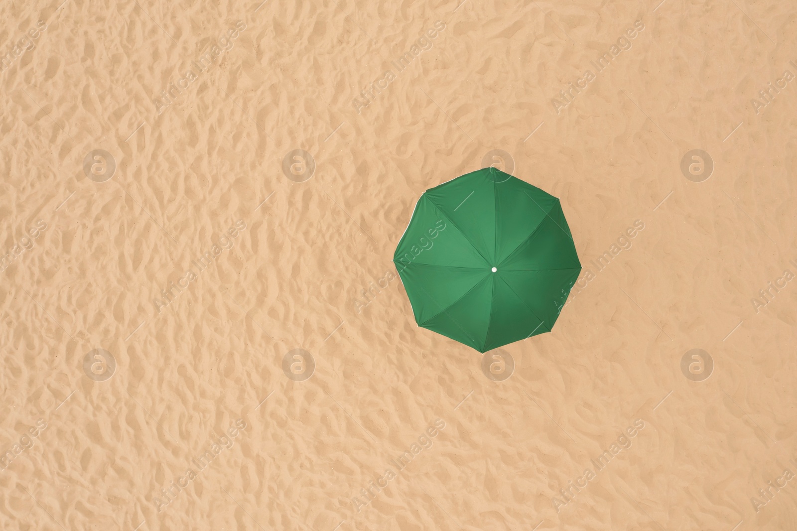 Image of Green beach umbrella on sandy coast, aerial view. Space for text