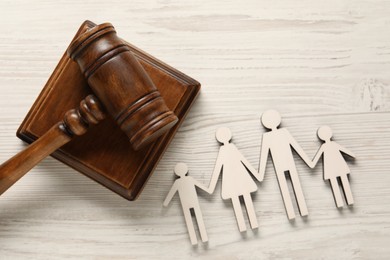 Law concept. Gavel and figures of parents with children on white wooden table, top view