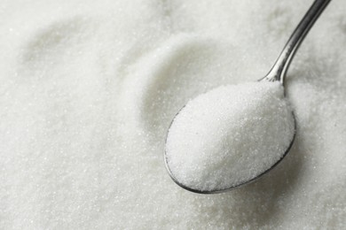 Metal spoon on granulated sugar, closeup view