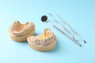 Photo of Dental model with gums and dentist tools on light blue background. Cast of teeth