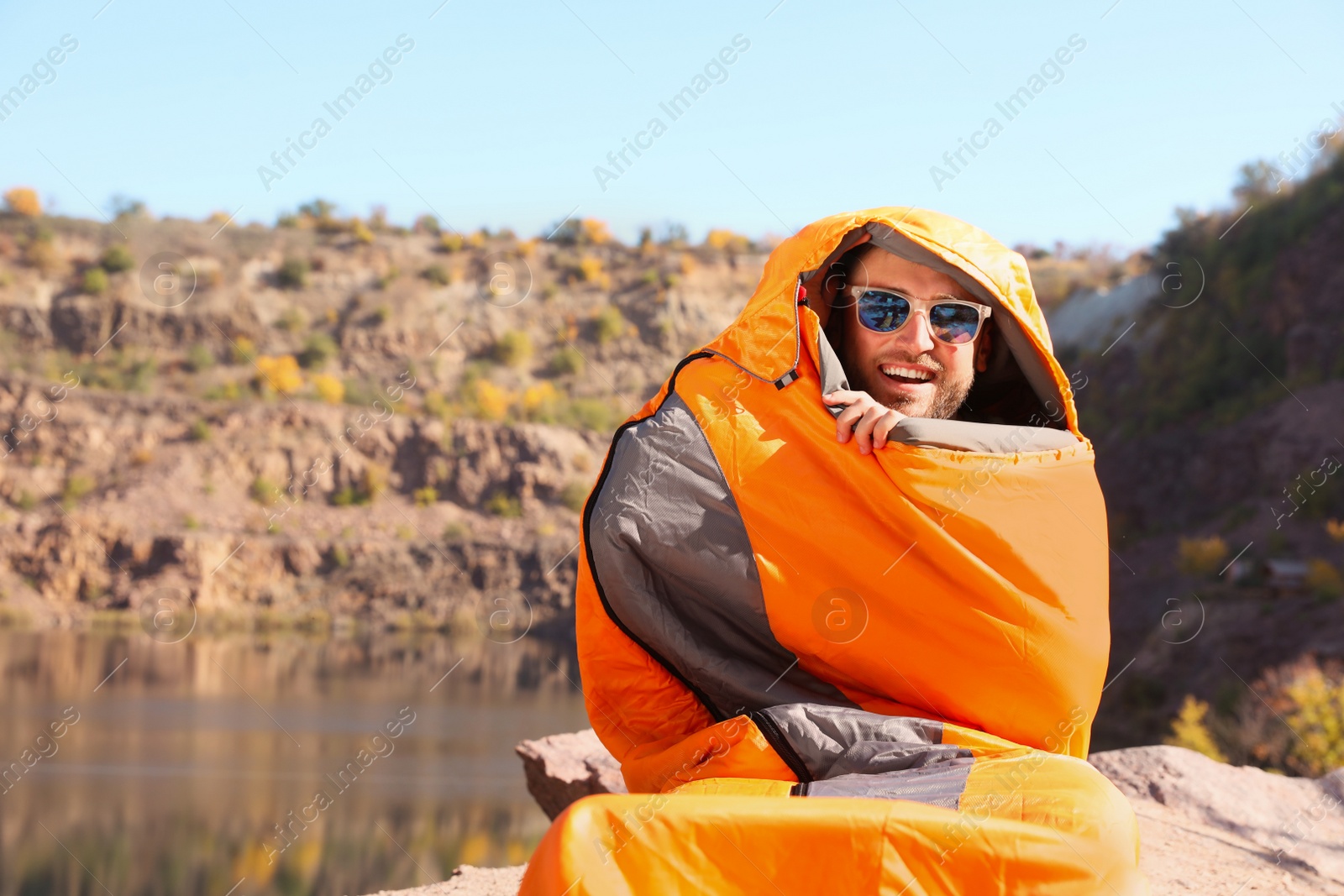 Photo of Young male camper in sleeping bag outdoors. Space for text