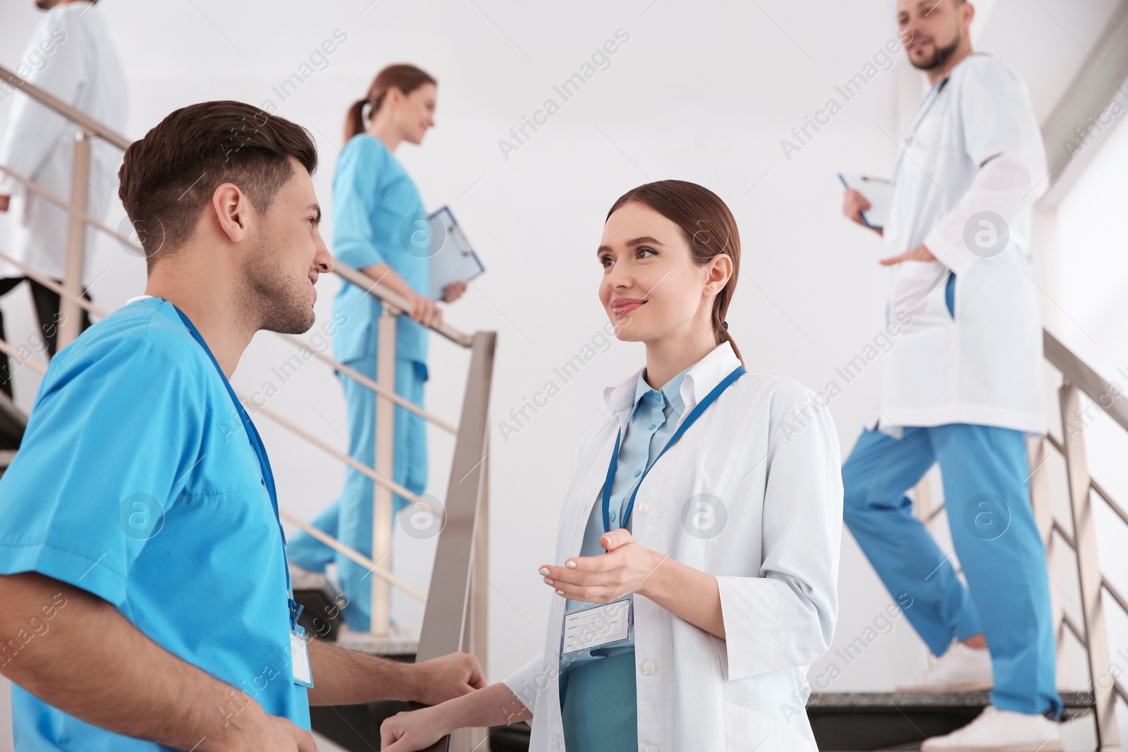 Photo of Female doctor talking to colleague on staircase in clinic