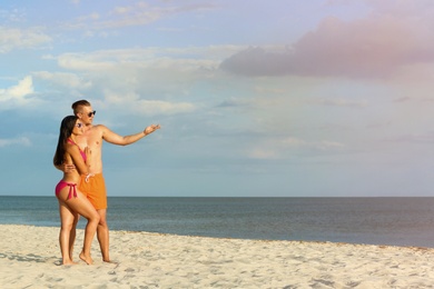 Young woman in bikini spending time with her boyfriend on beach. Lovely couple