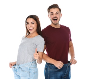 Photo of Fit people in oversized jeans on white background. Weight loss