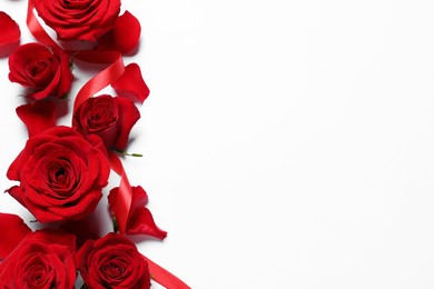 Beautiful red roses, petals and ribbon on white background, flat lay. Space for text