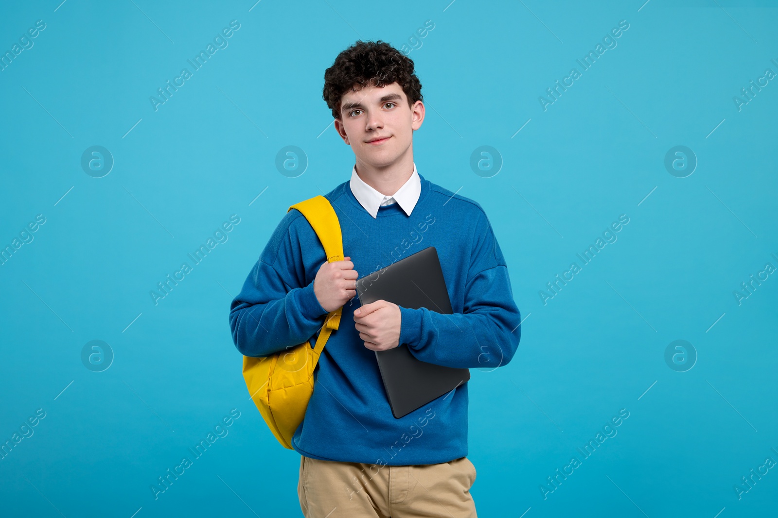 Photo of Portrait of student with backpack and laptop on light blue background