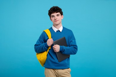 Portrait of student with backpack and laptop on light blue background