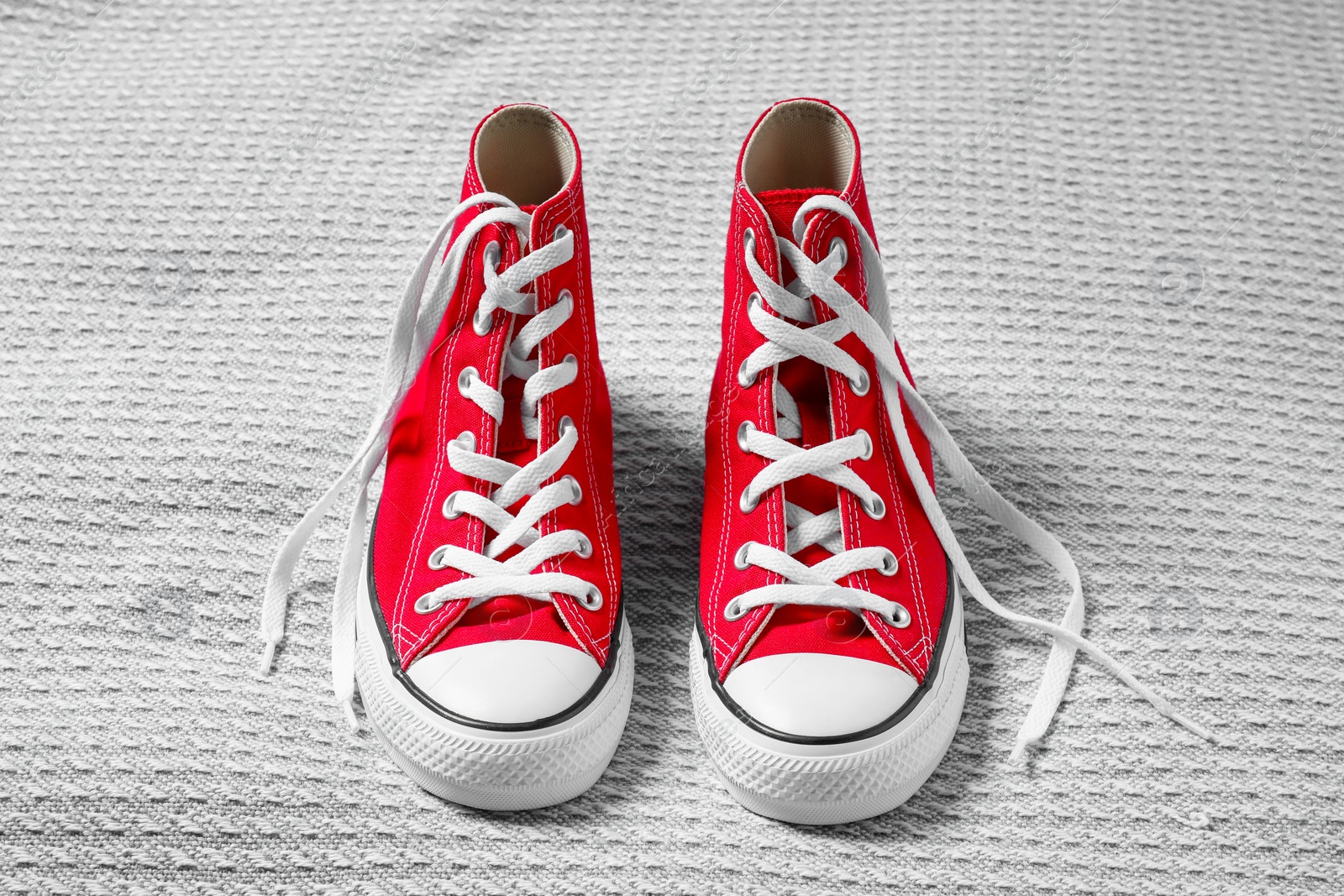 Photo of Pair of new stylish red sneakers on light grey fabric