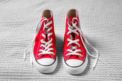 Photo of Pair of new stylish red sneakers on light grey fabric