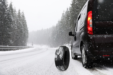 Snow tire near car on road in winter