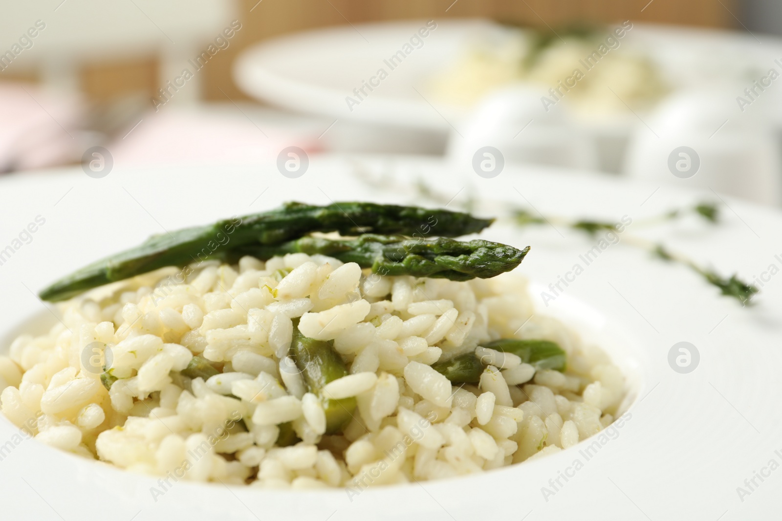 Photo of Delicious risotto with asparagus in plate, closeup