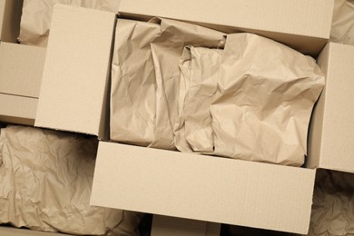 Photo of Many open cardboard boxes with crumpled paper as background, top view