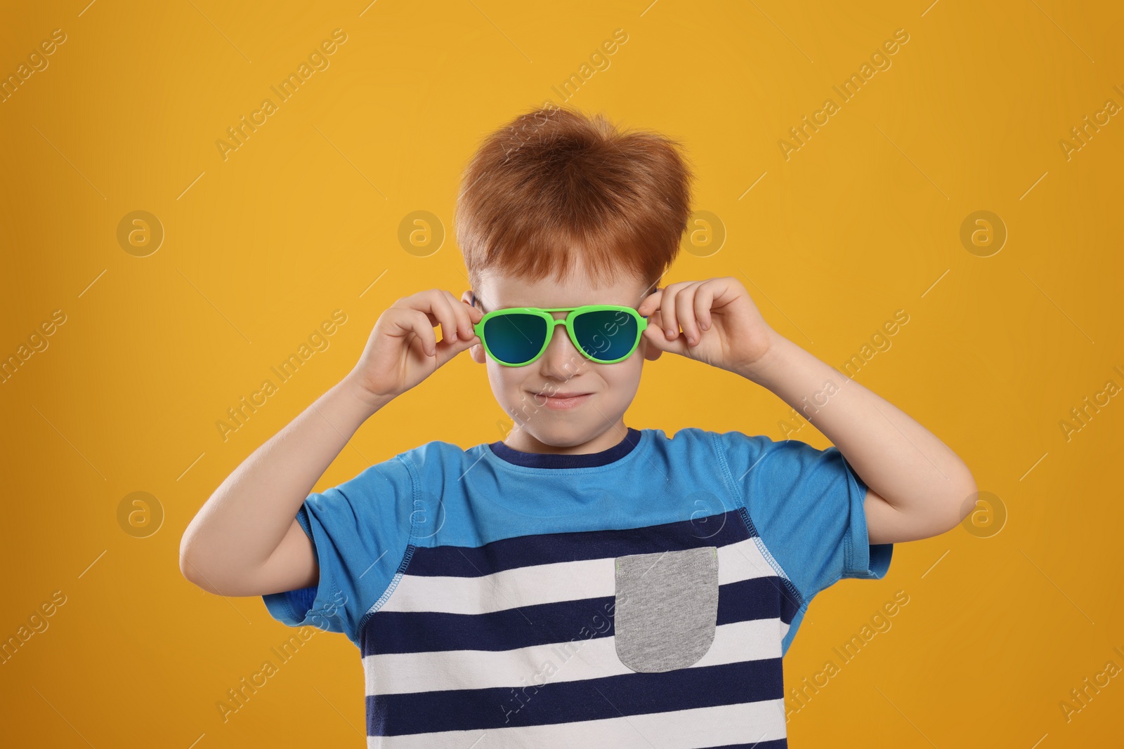 Photo of Cute little boy with sunglasses on yellow background