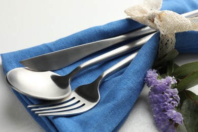 Photo of Stylish setting with cutlery and napkin on white textured table, closeup