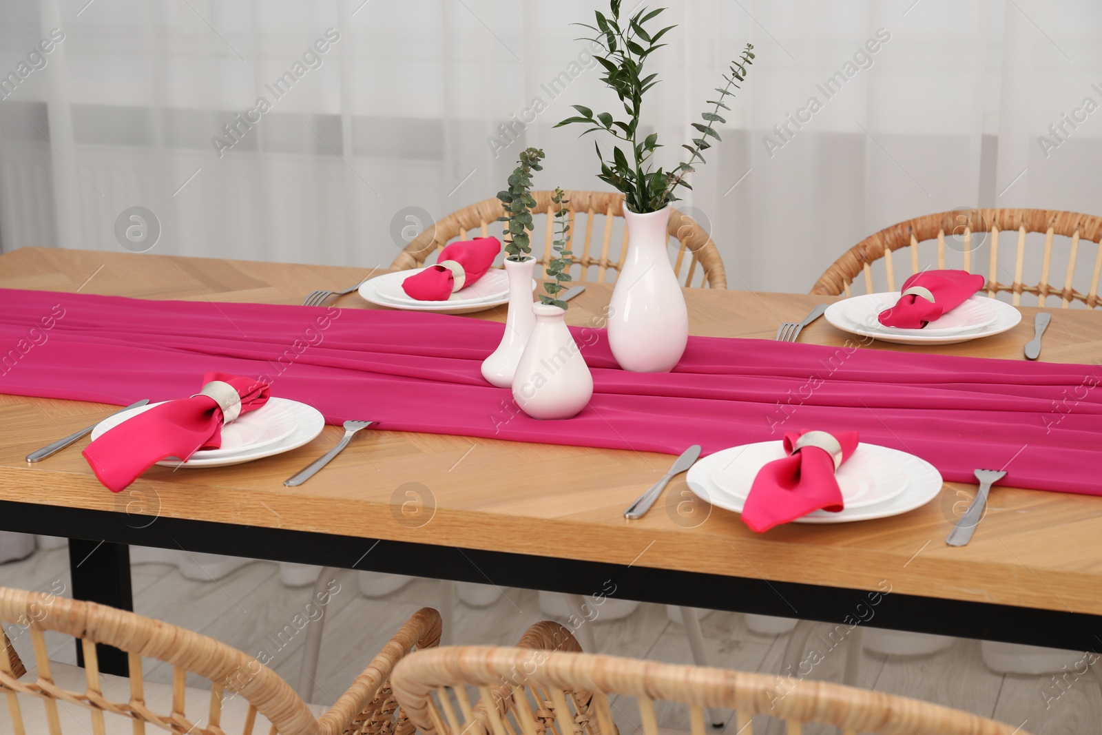 Photo of Beautiful table setting and vases with green branches in dining room