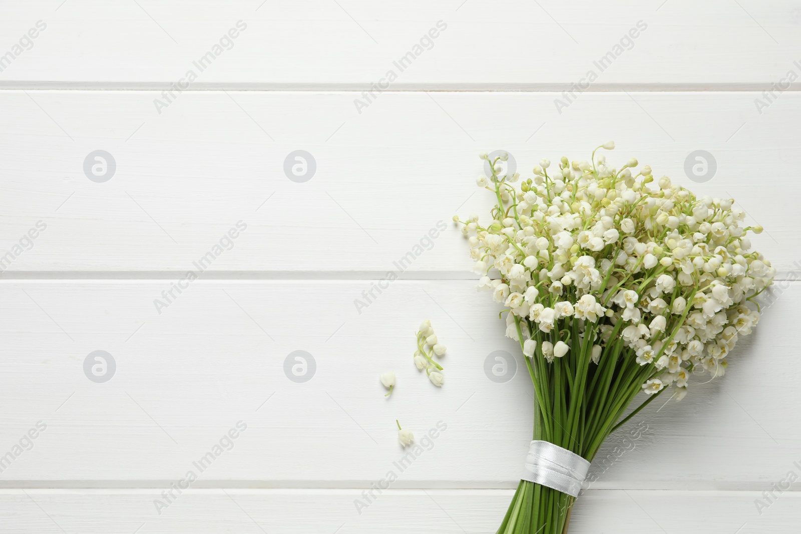 Photo of Beautiful lily of the valley bouquet on white wooden table, top view. Space for text