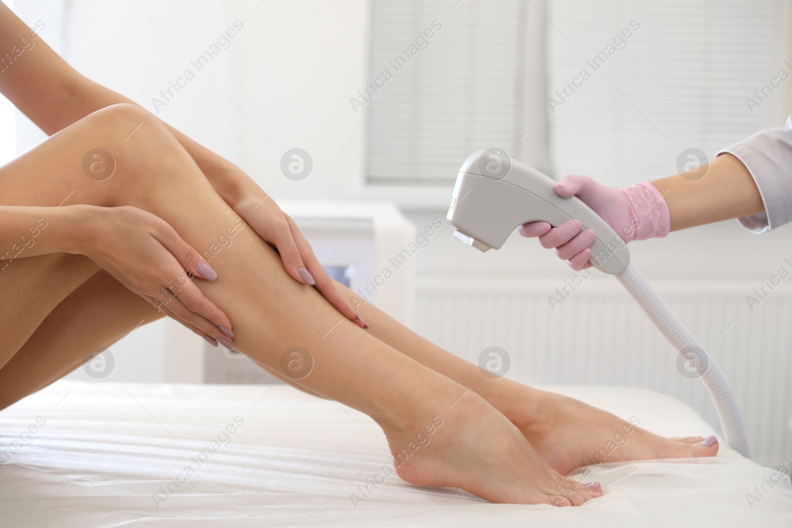 Photo of Young woman undergoing laser epilation procedure in beauty salon, closeup