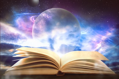 Wooden table with open book and beautiful universe on background