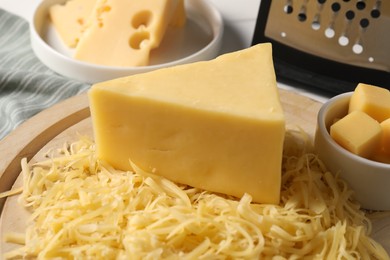 Photo of Grated and whole pieces of cheese on table, closeup