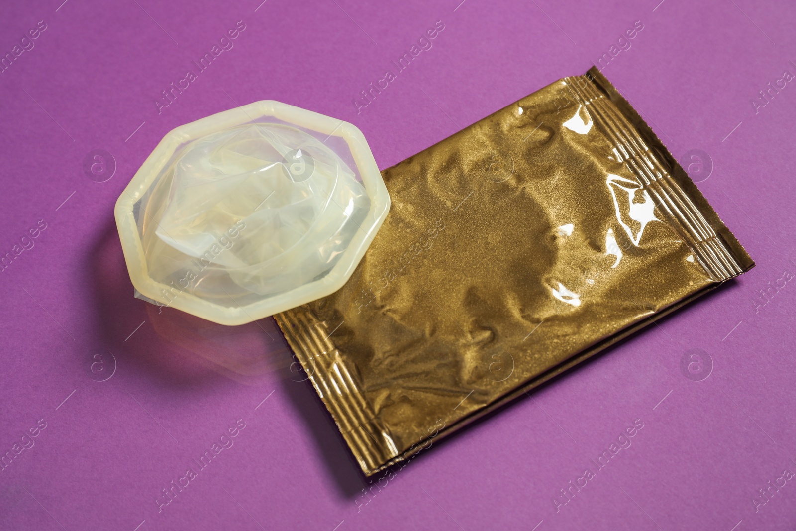 Photo of Unpacked female condom and package on violet background, closeup. Safe sex