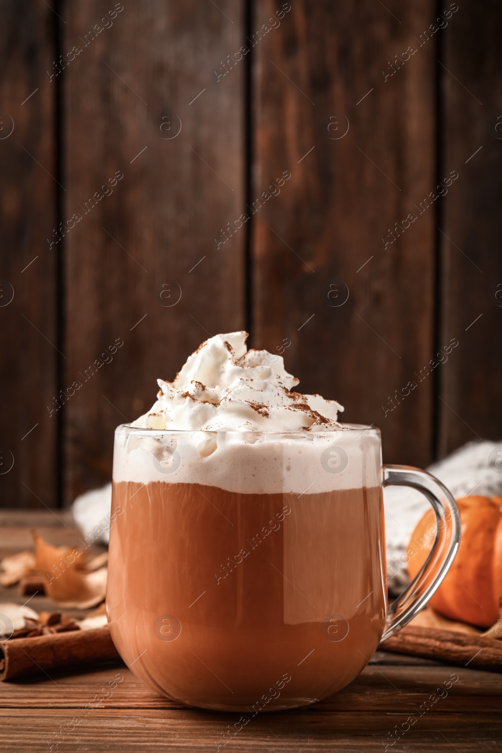 Photo of Delicious pumpkin latte on wooden table, closeup