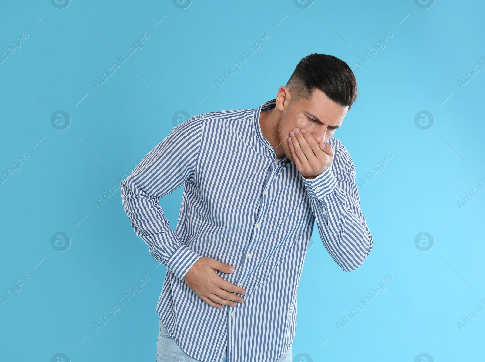 Photo of Man suffering from stomach ache and nausea on light blue background. Food poisoning