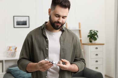 Photo of Diabetes test. Man checking blood sugar level with glucometer at home