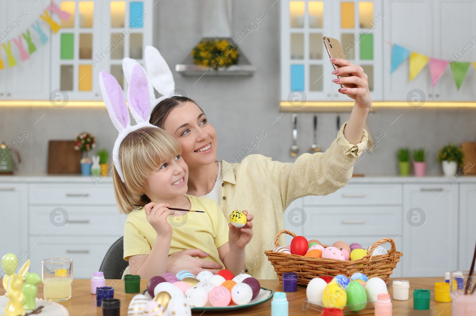 Photo of Mother making selfie with her cute son at table in kitchen. Painting Easter eggs