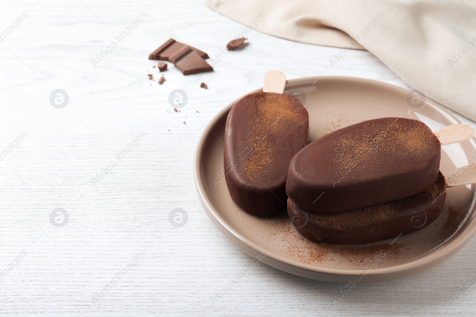 Photo of Delicious glazed ice cream bars on white wooden table. Space for text