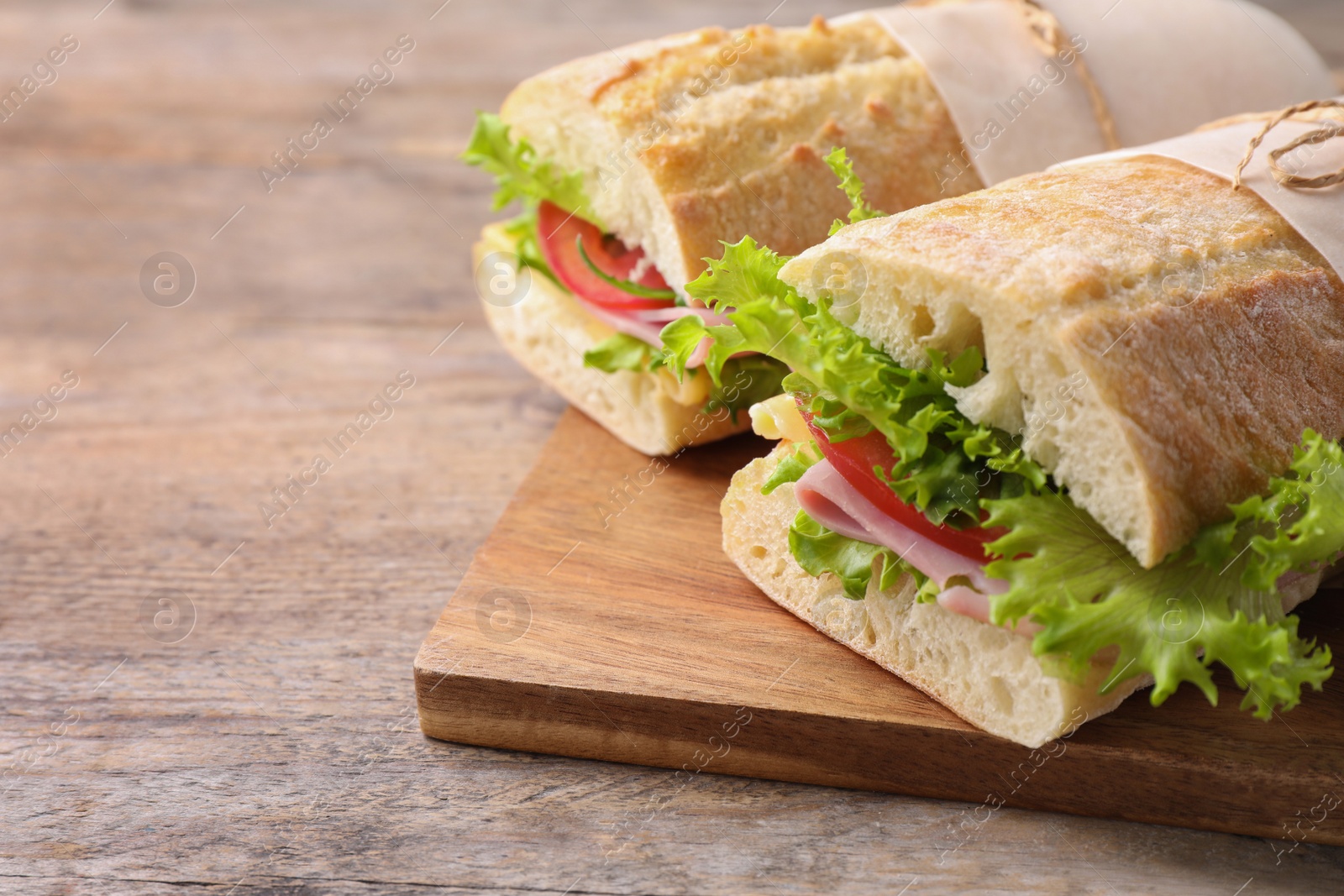 Photo of Tasty sandwiches with ham on wooden table, closeup