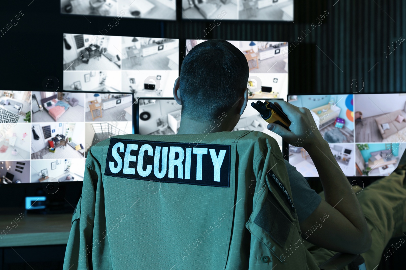 Photo of Security guard with portable transmitter monitoring modern CCTV cameras indoors