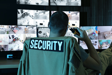 Photo of Security guard with portable transmitter monitoring modern CCTV cameras indoors