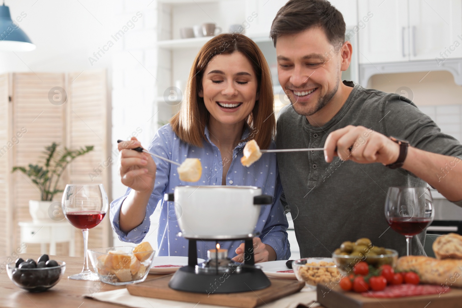 Photo of Happy couple enjoying fondue dinner at home