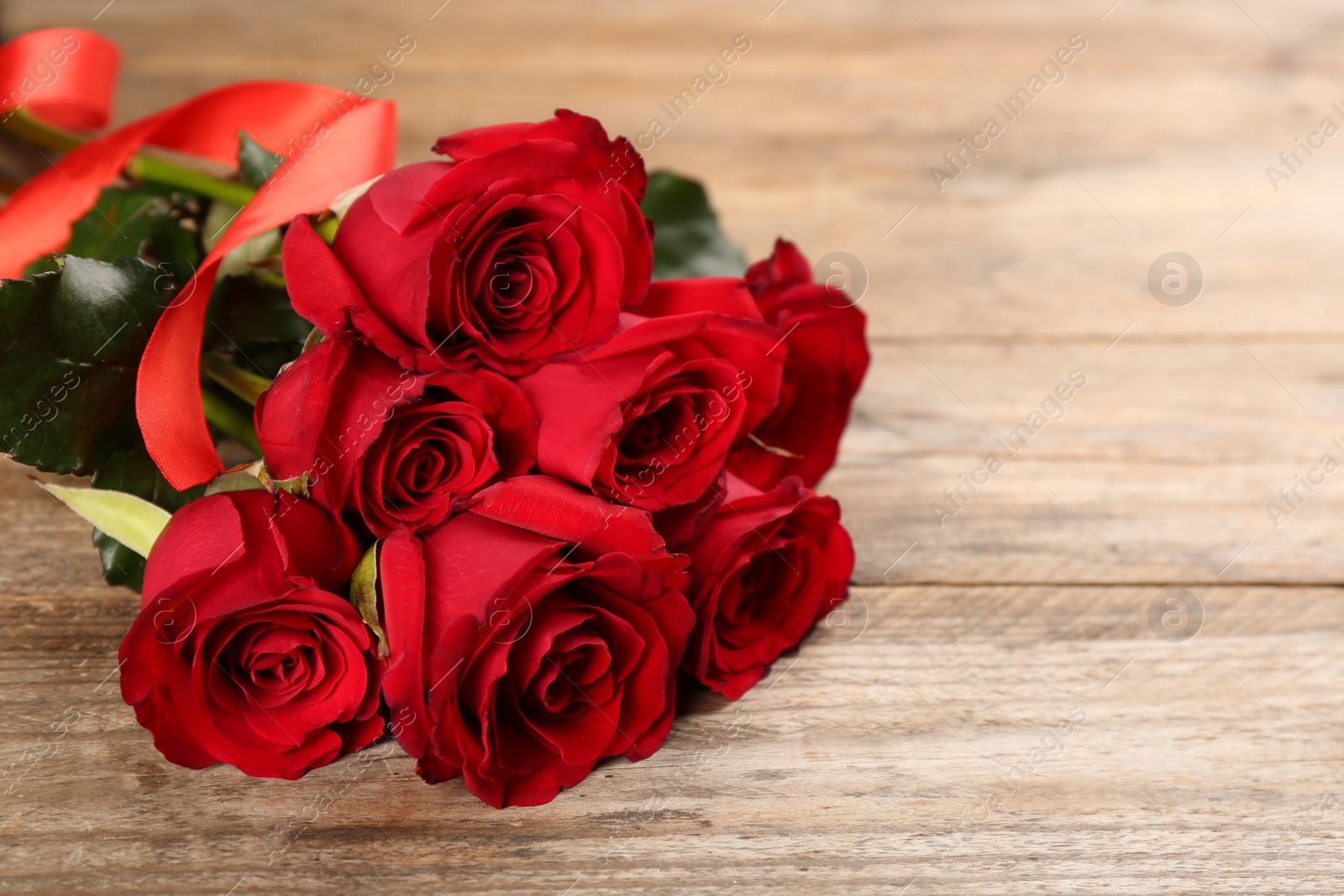 Photo of Beautiful red roses on wooden table, space for text. Valentine's Day celebration