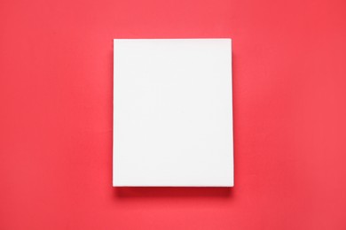 Photo of Blank canvas on red background, top view. Space for design