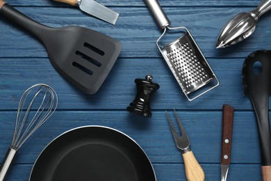 Photo of Set of different kitchen utensils on blue wooden table, flat lay