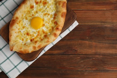 Fresh homemade khachapuri with cheese and egg on wooden table, top view. Space for text