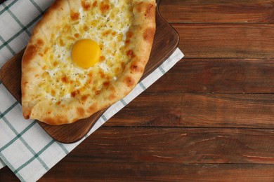 Photo of Fresh homemade khachapuri with cheese and egg on wooden table, top view. Space for text