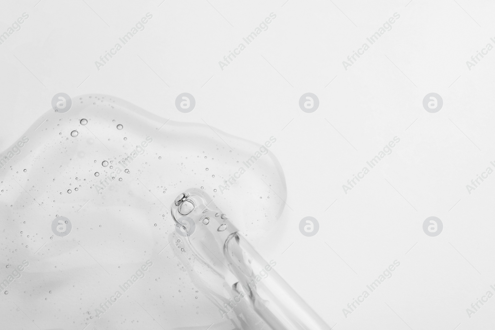 Photo of Dripping cosmetic oil from pipette onto light surface, closeup. Space for text